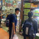นักเรียนสองคนกำลังยืนเลือกซื้อของในร้านของที่ระลึกภายในตลาด